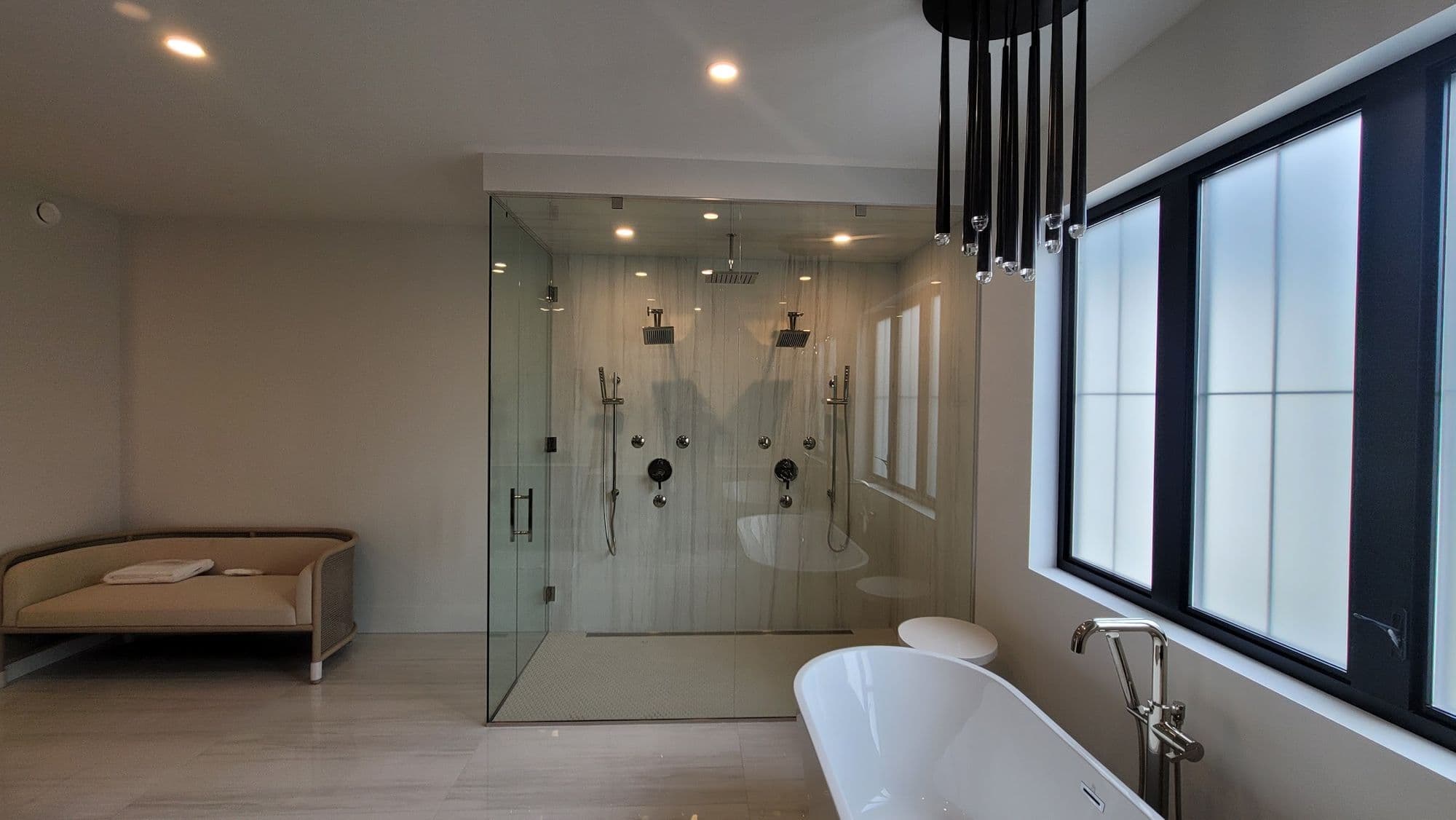 Renovated master bathroom with a walk-in glass shower and freestanding tub