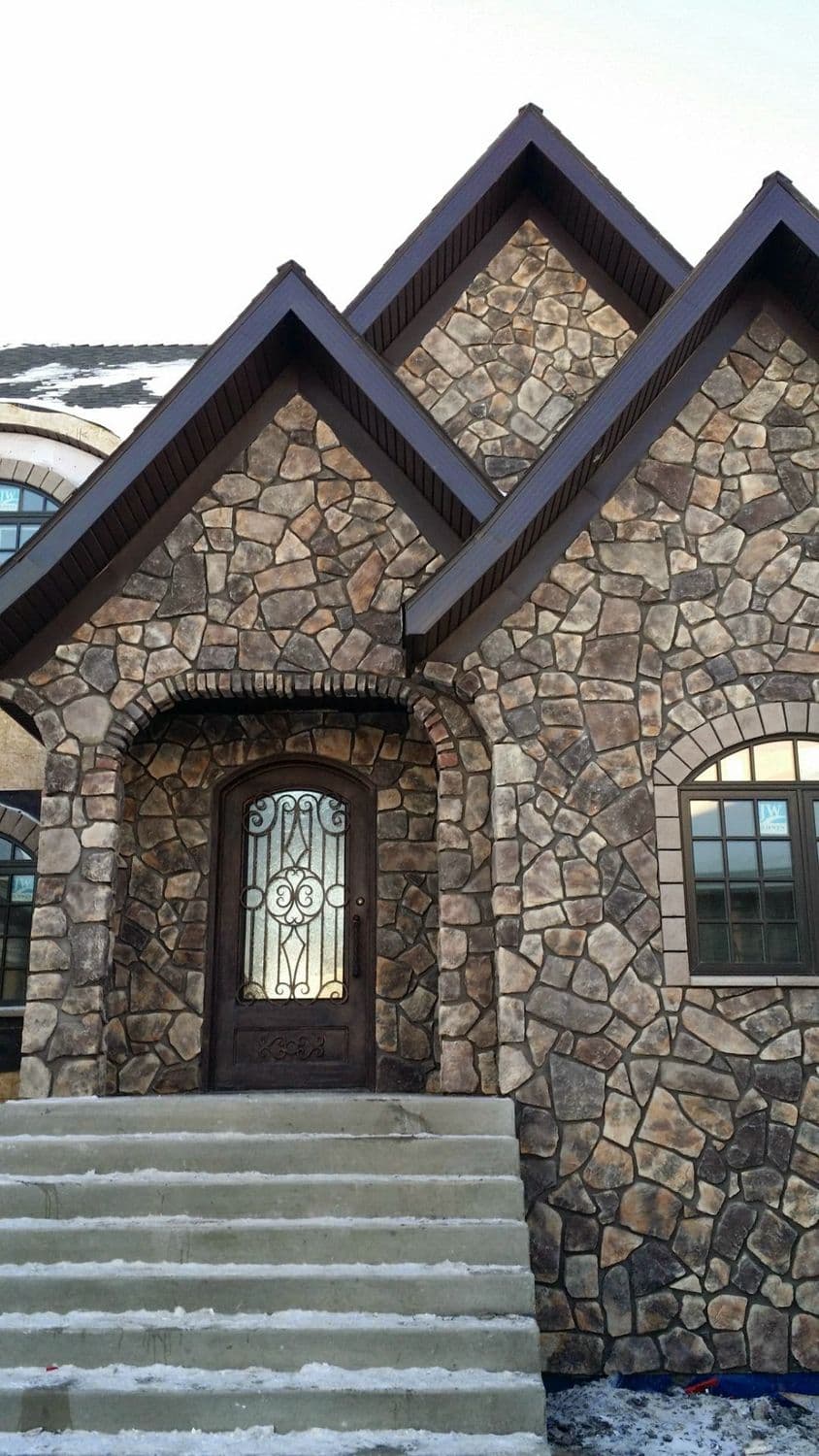 Stone veneer entry with an arched door and poured concrete steps