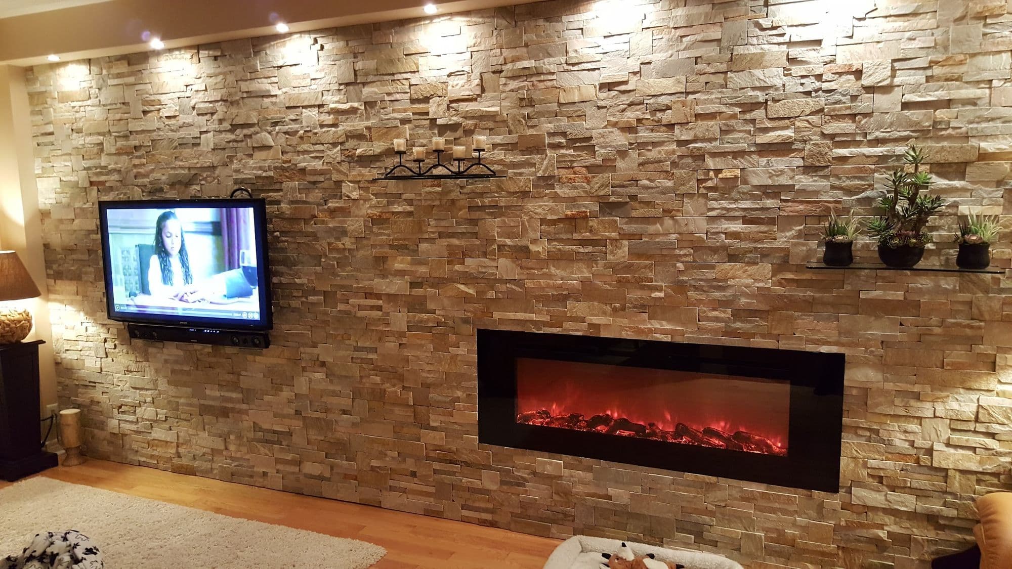 Interior stacked-stone feature wall with a linear fireplace, lit from above