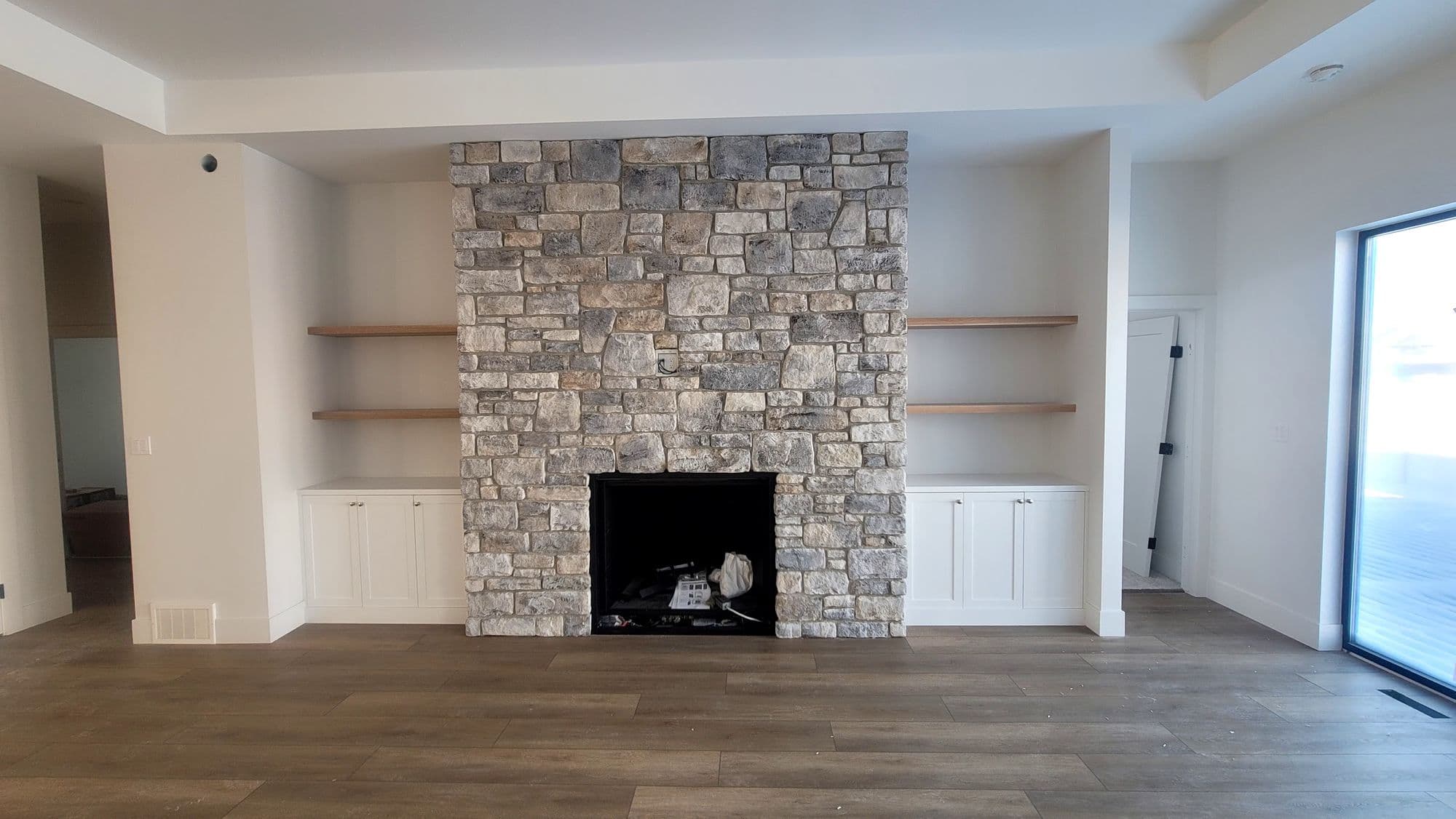 Grey stone fireplace surround with floating timber shelves either side