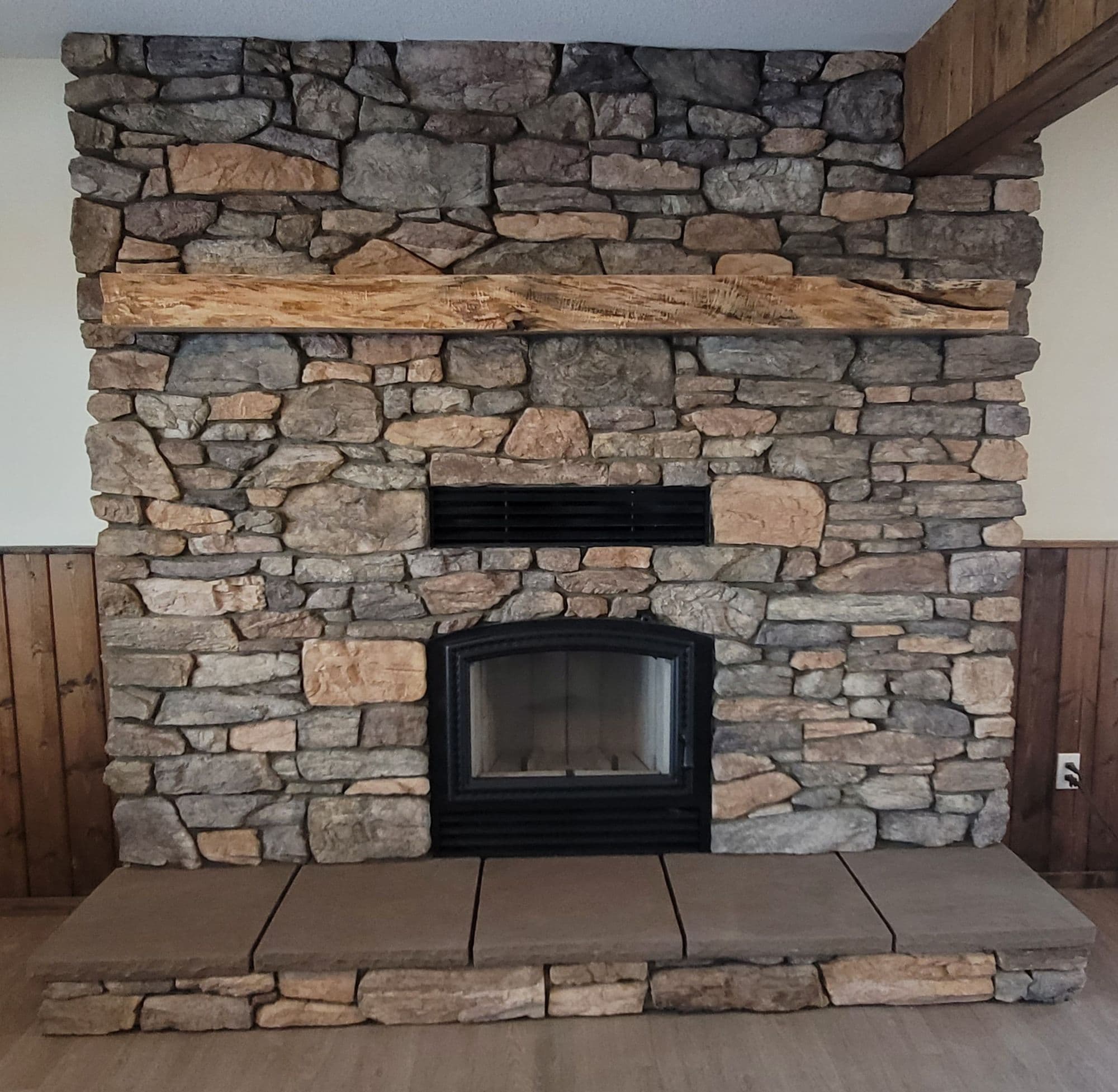 Full-height stone fireplace with a reclaimed timber mantel