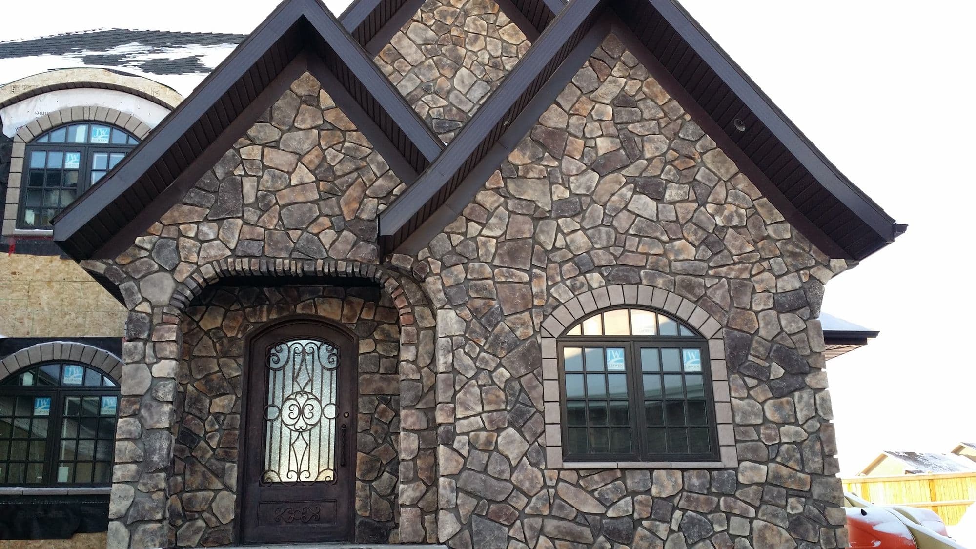 Natural stone veneer on the front gable and arched entry of a DWL-built home