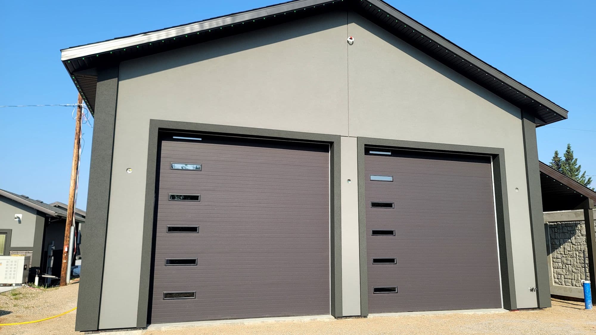 Newly stuccoed detached double garage with dark overhead doors