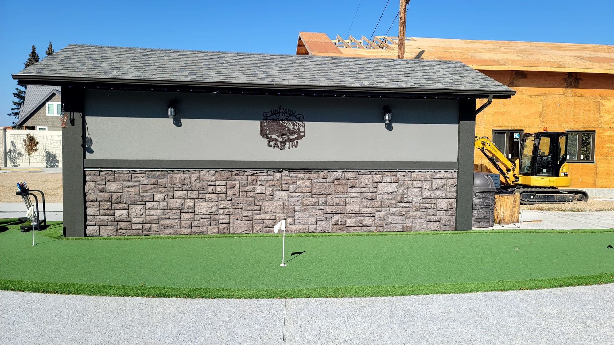 Shop building finished in stucco over a stone skirt beside a putting green