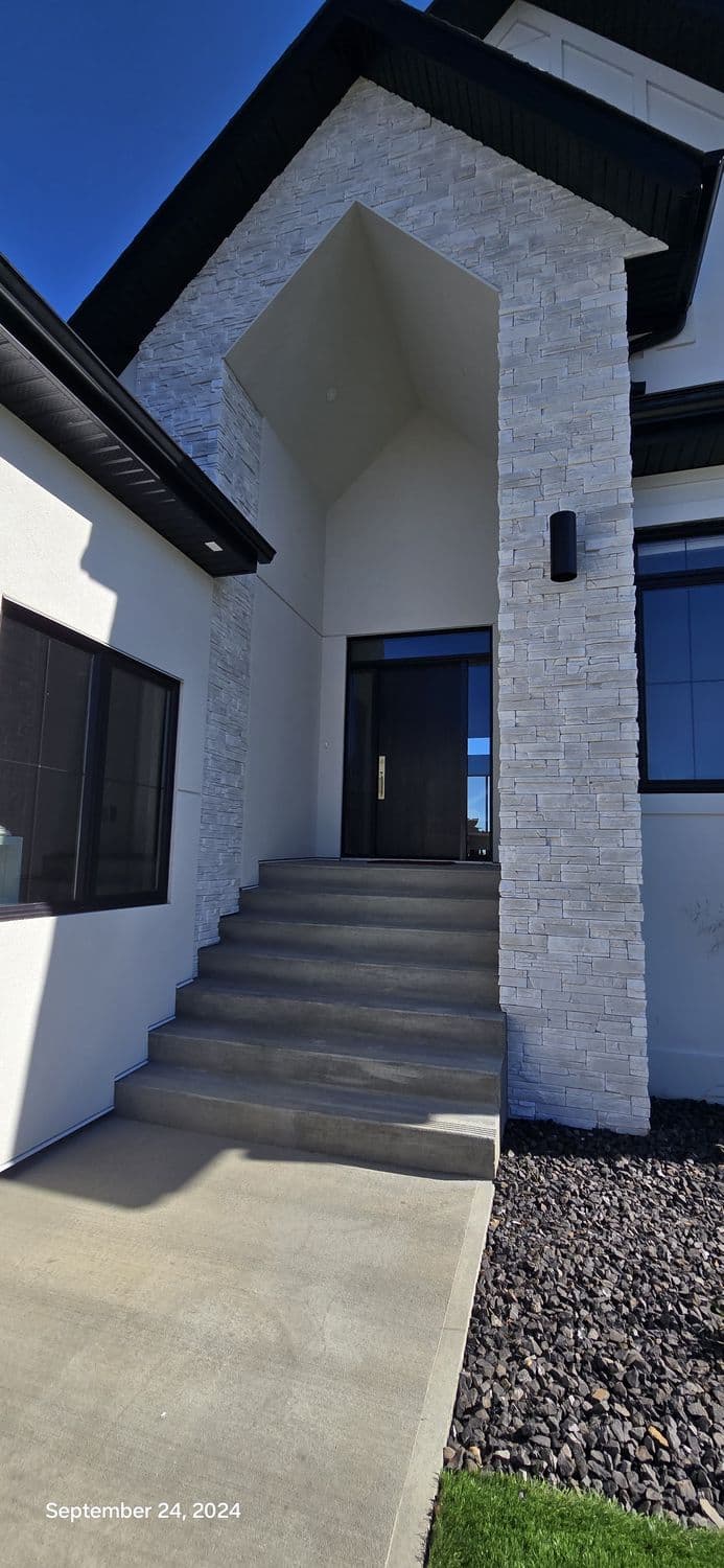 Light stone veneer wrapping the entry tower of a modern white house