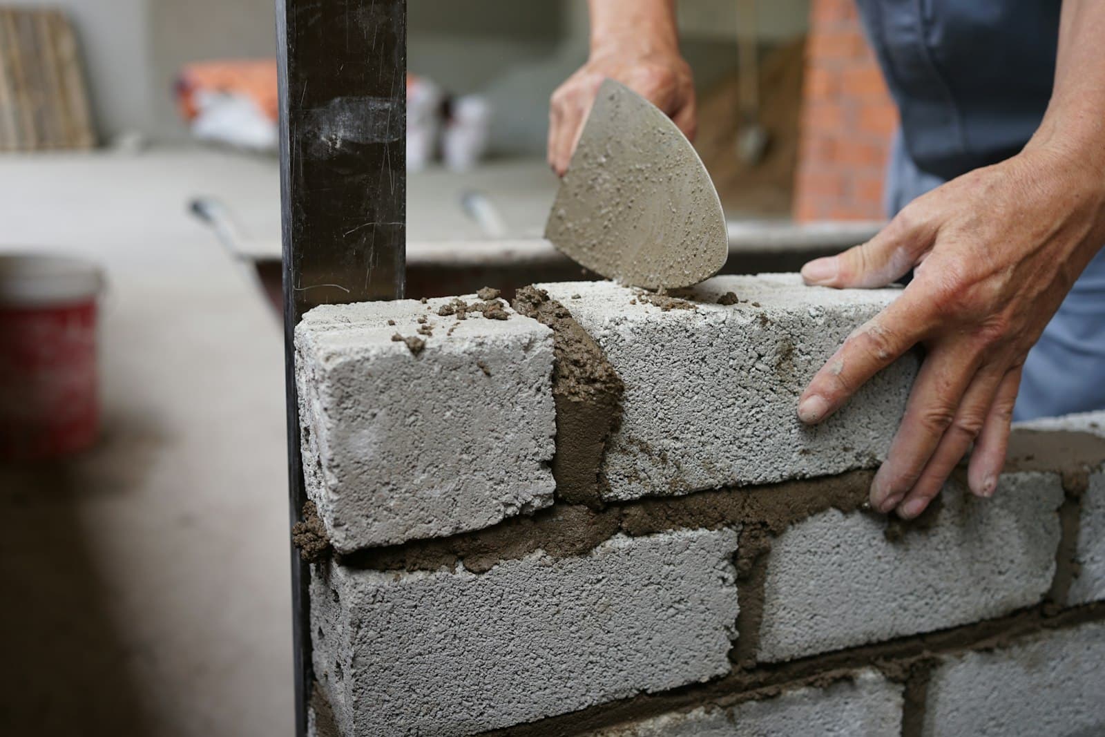 Mason laying brick with mortar — hands and trowel