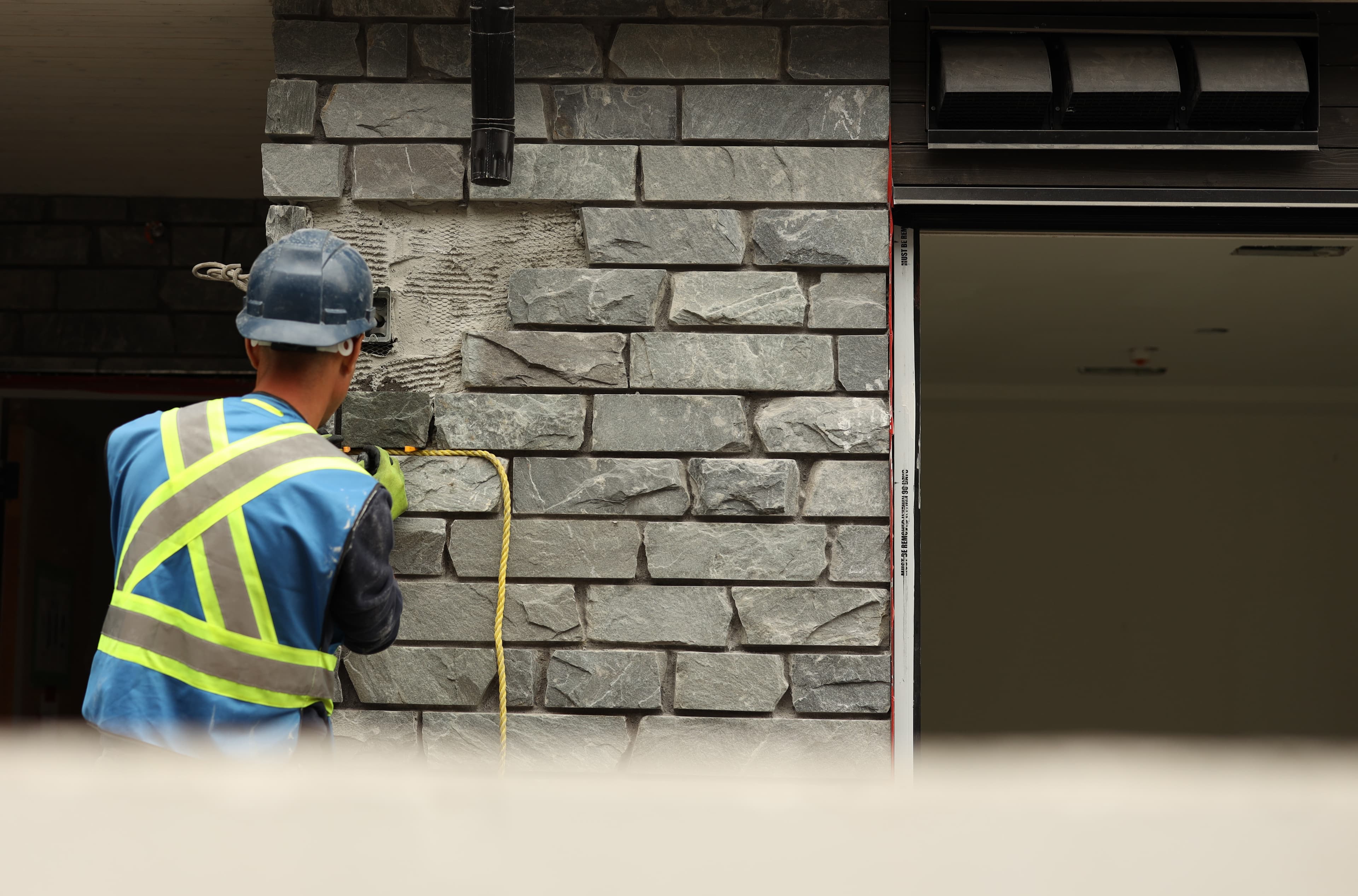 DWL mason installing stone veneer on an exterior wall